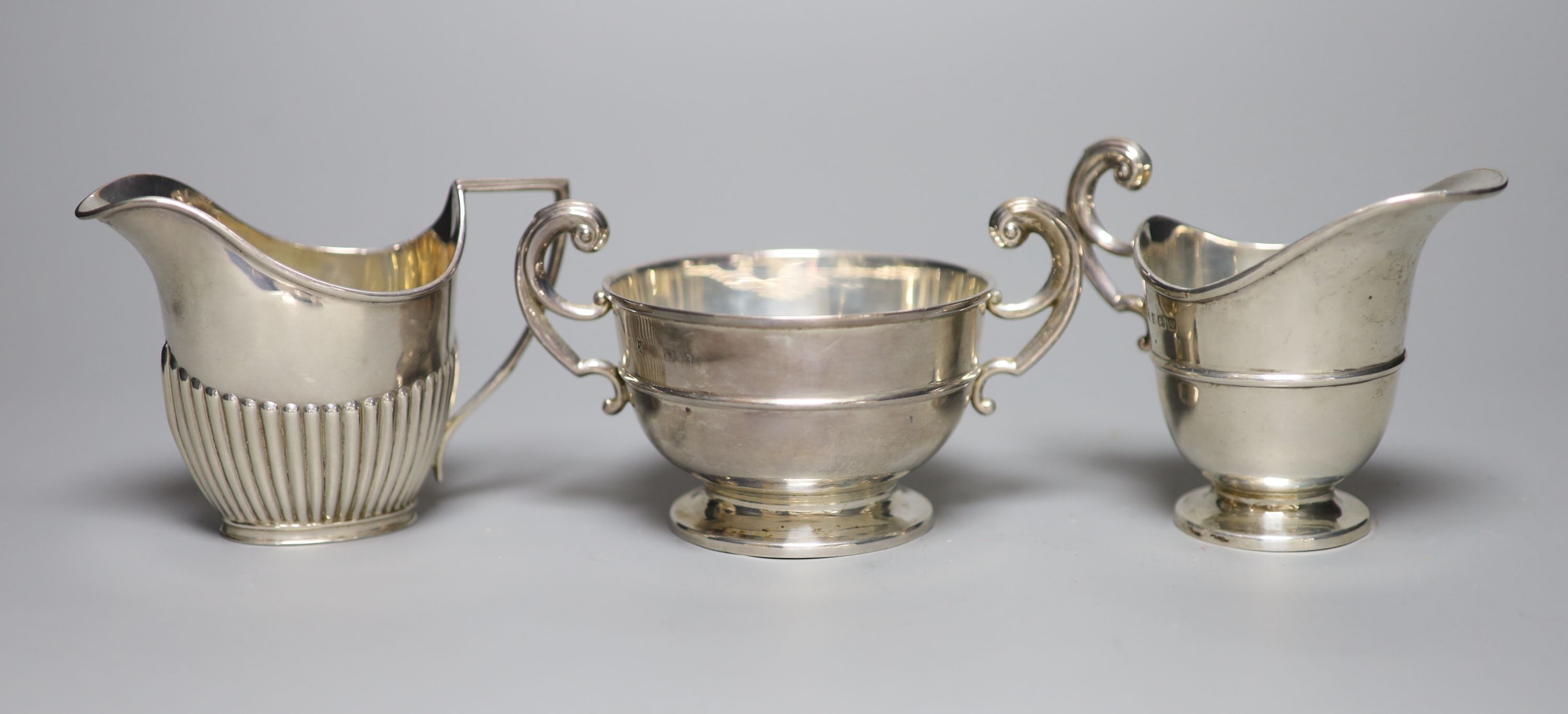 An Edwardian silver cream jug and sugar bowl, Birmingham, 1909, a demi fluted silver cream jug and a silver toastrack